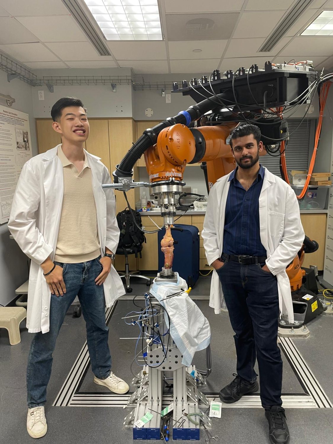 The Hippos founders in lab coats beside the simVITRO robotic arm with a cadaveric knee specimen mounted, Cleveland Clinic BioRobotics Lab.