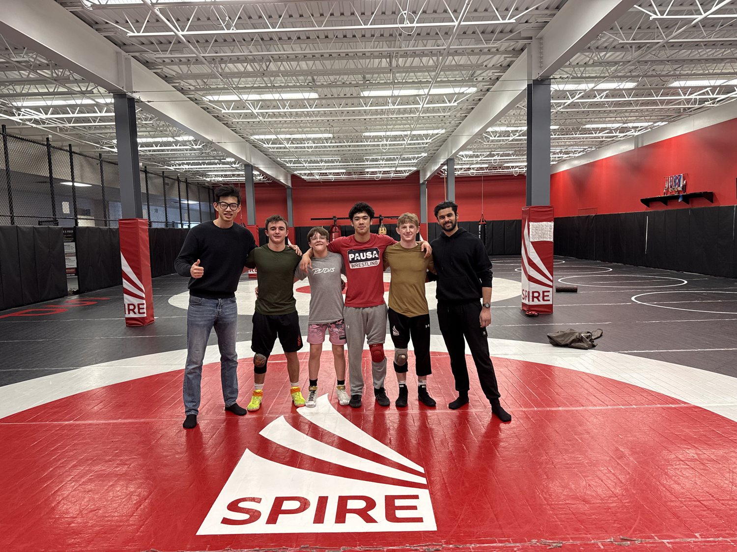 The Hippos founders with SPIRE athletes on the wrestling mat, athletes wearing the Hippos knee sleeve.